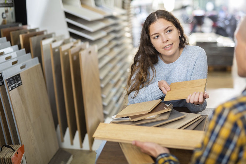 Женщина в магазине выбирает напольное покрытие.