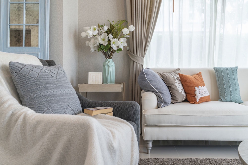 Интерьер гостиной, подушки и пледы на диване и кресле.