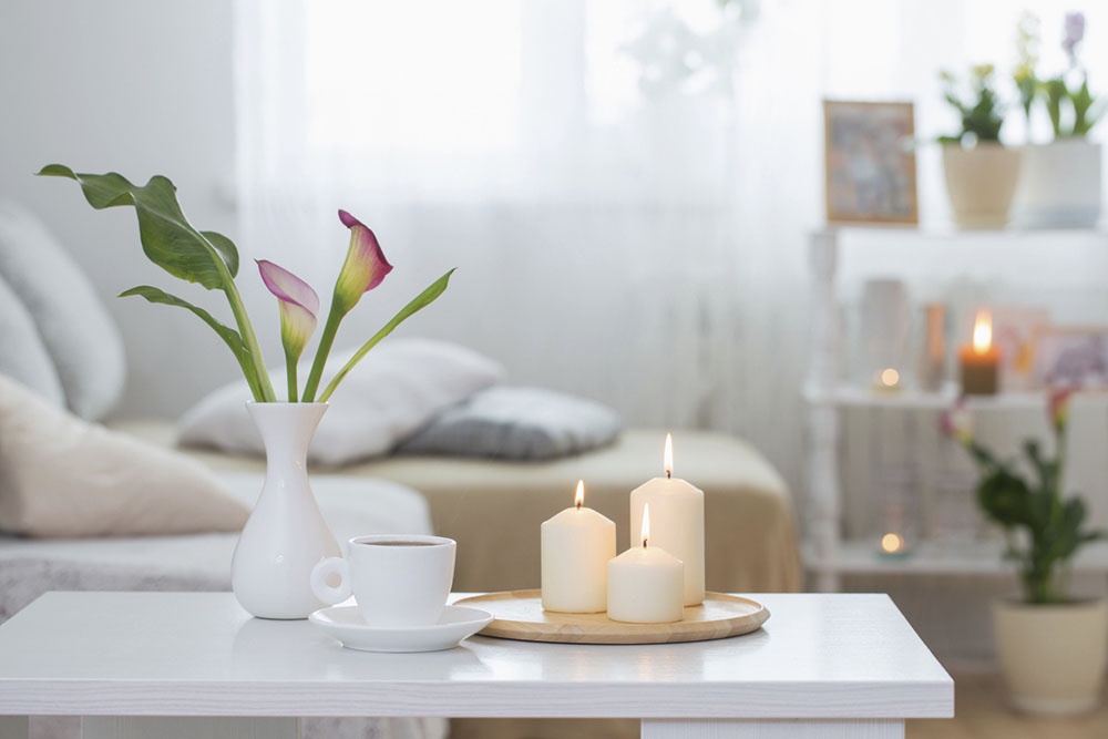 Свечи и цветы на столике у дивана.