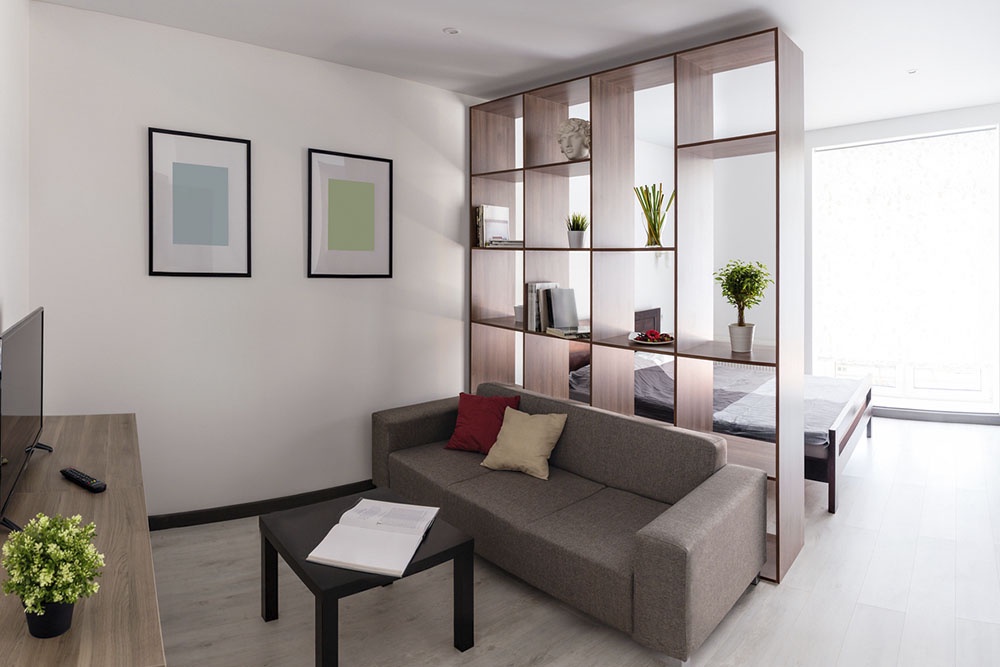 Cтеллаж или этажерка с книгами, поставленные перпендикулярно стене, зонирование в комнате.