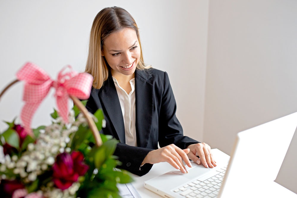 Женщина за рабочим столом читает поздравительное письмо от компании.