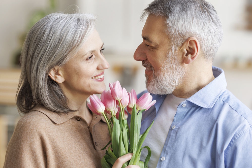 Мужчина поздравляет женщину с 8 Марта, дарит тюльпаны.