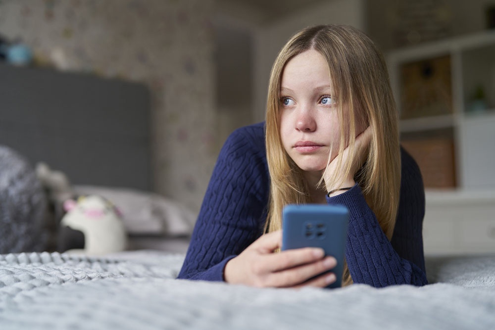 Девочка с телефоном в руках, плачет прочитав сообщение.