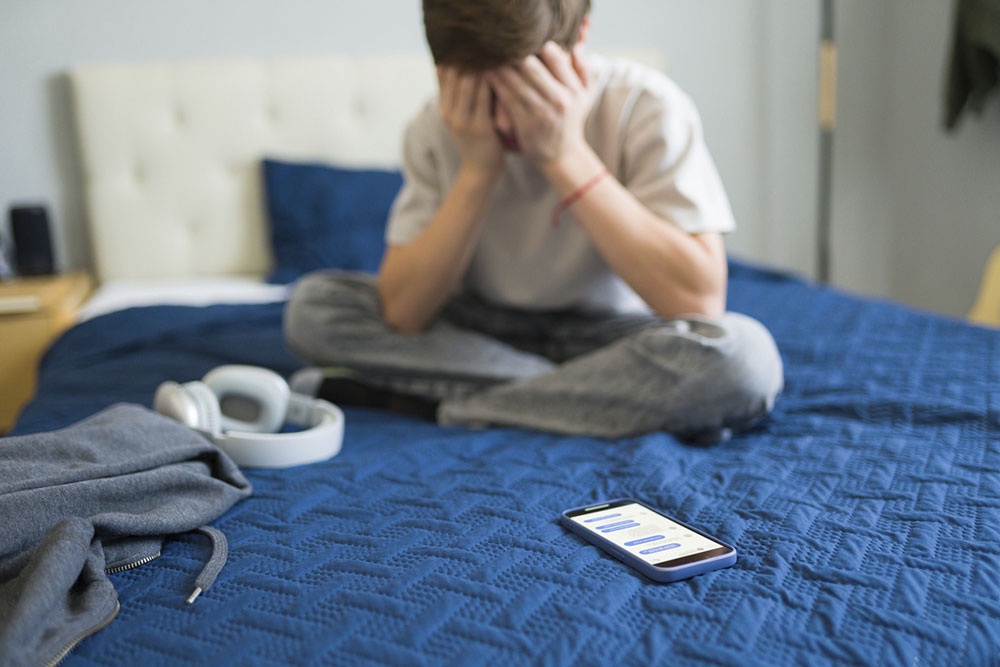 Ребенок грустит и нервничает из-за неприятных сообщений в телефоне.