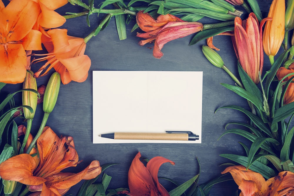 Лист бумаги, ручка, оранжевые лилии.
