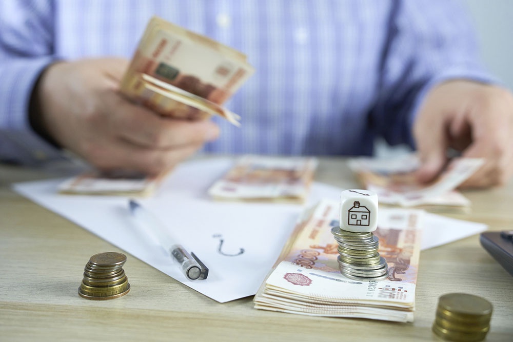 Человек считает купюры, платеж по ипотеке.