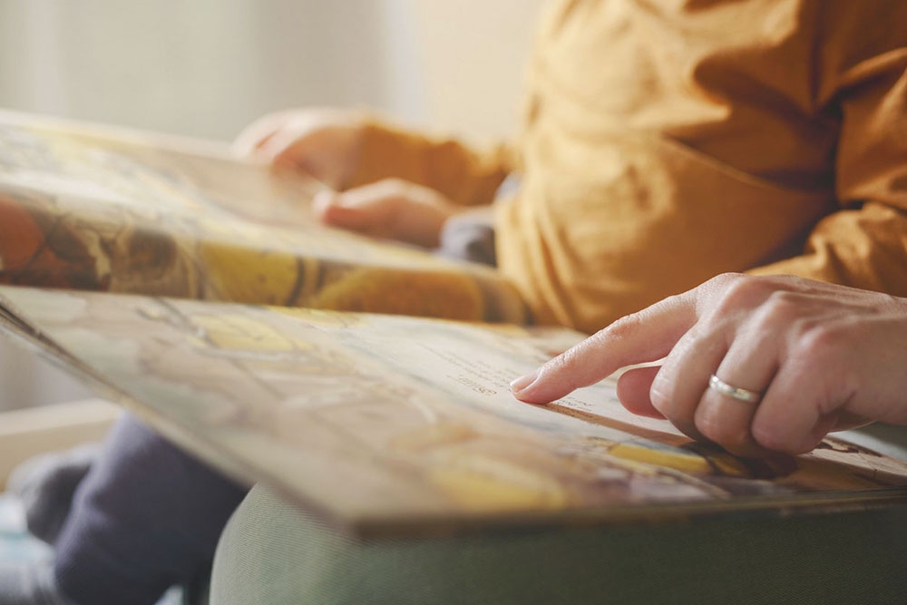 Мама читает ребенку красочную книгу.