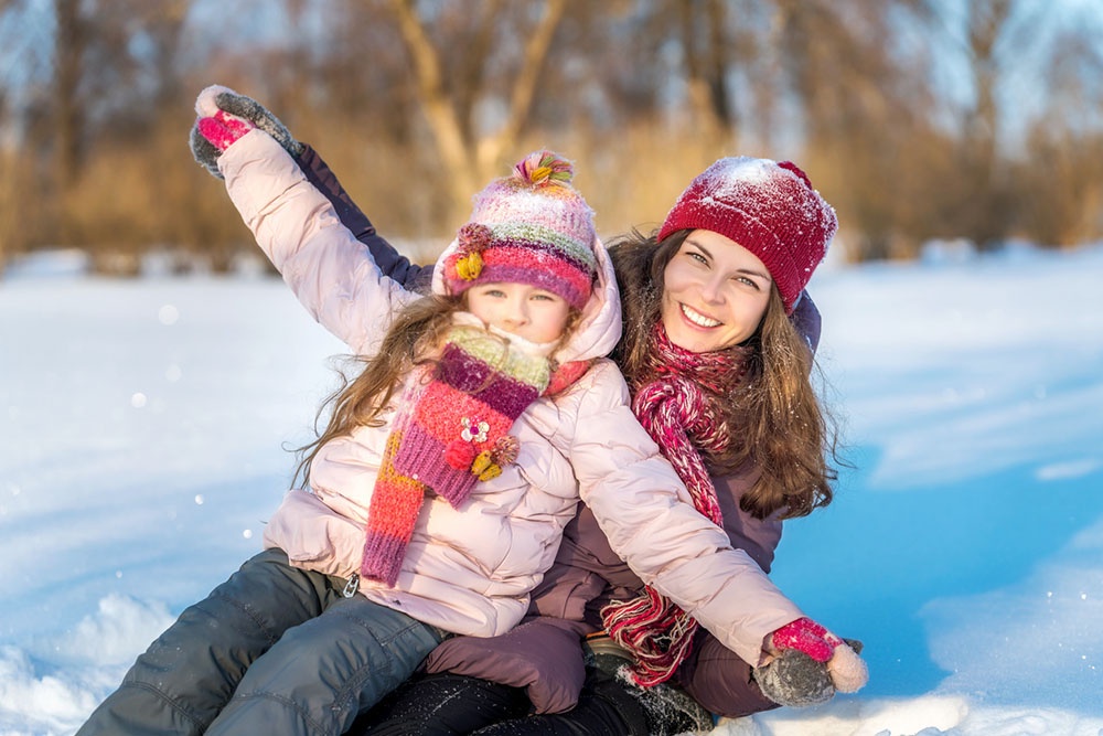 Мама и дочь кататься на тюбингах в парк, чтобы отпраздновать день снега.