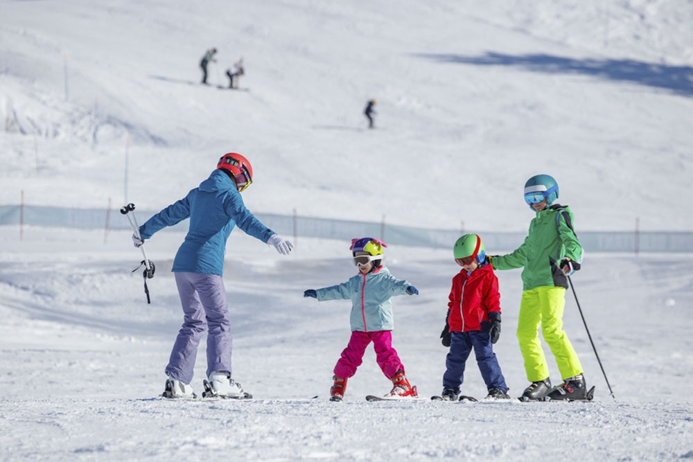 Инструктор работает с детьми на горнолыжном склоне.
