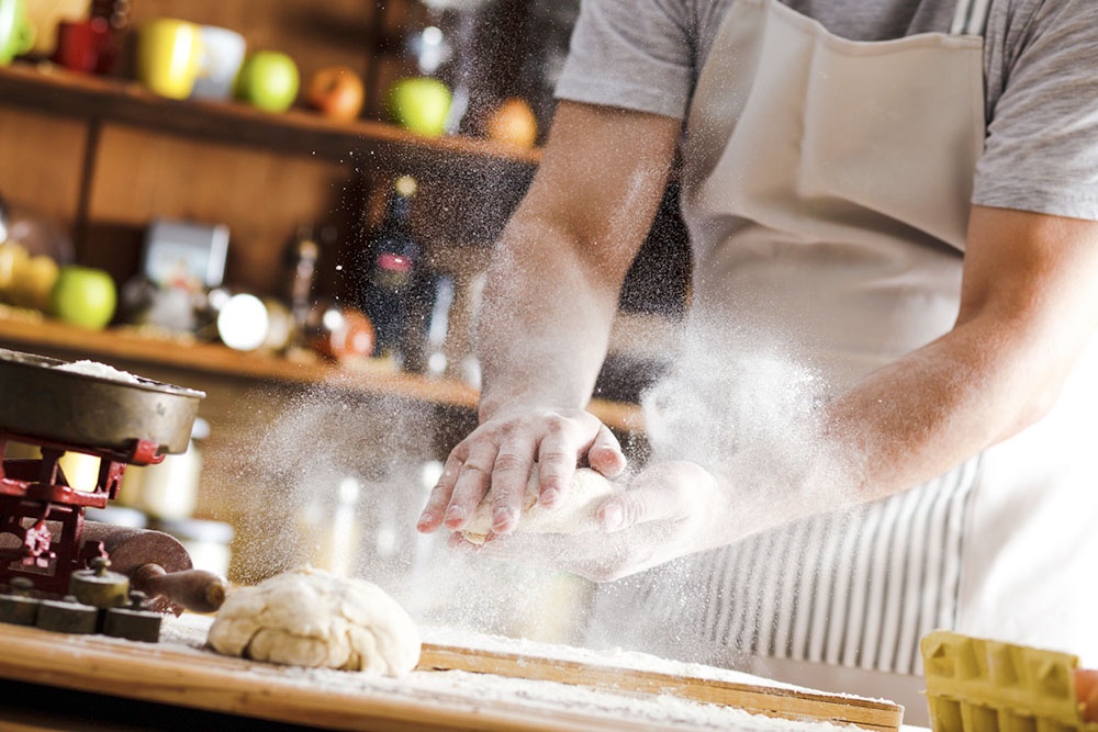 Мужчина вымешиввает тесто.