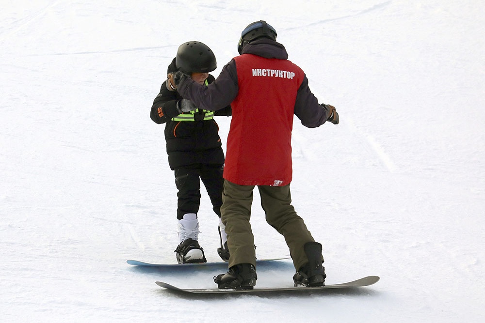 Инструктор занимается со сноубордистом