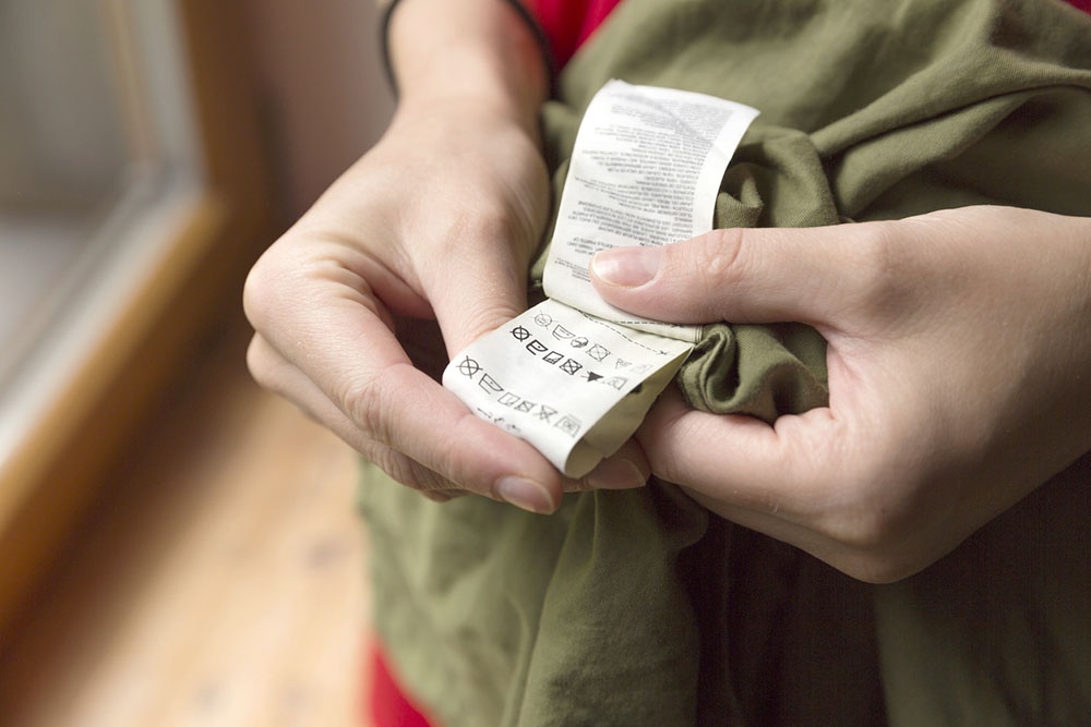 Человек проверяет бирку на одежде перед стиркой в машинке.