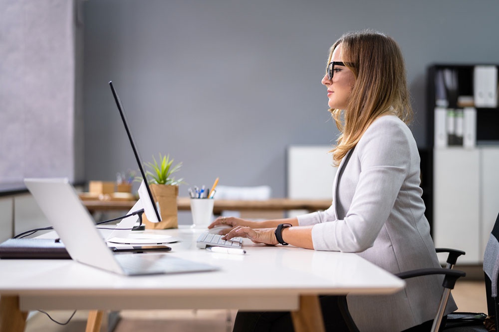Женщина в офисе сидит в кресле за рабочим столом.