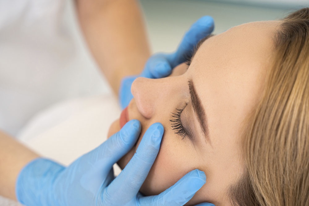 Врач осматривает лицо женщины на предмет отеков.