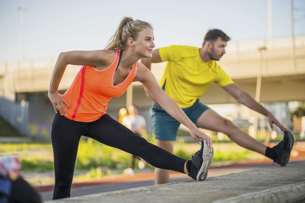 Мужчина и женщина разминаются перед забегом.