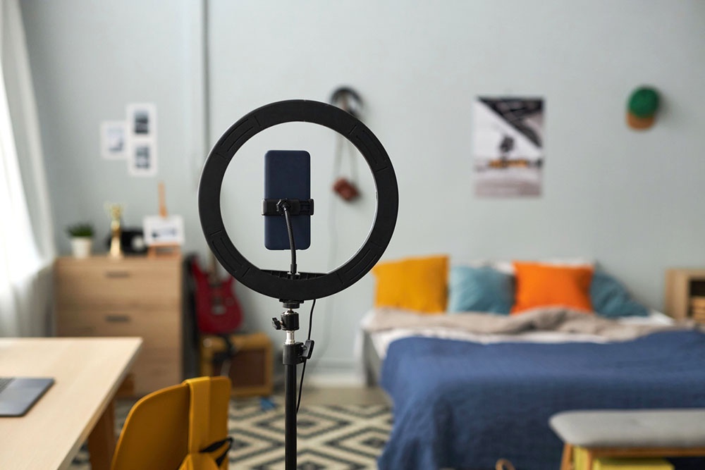 Смартфон на штативе и кольцевая лампа в детской спальне.