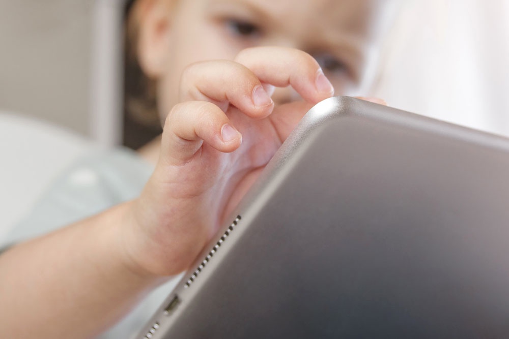 Ребенок изучает информацию на планшете.