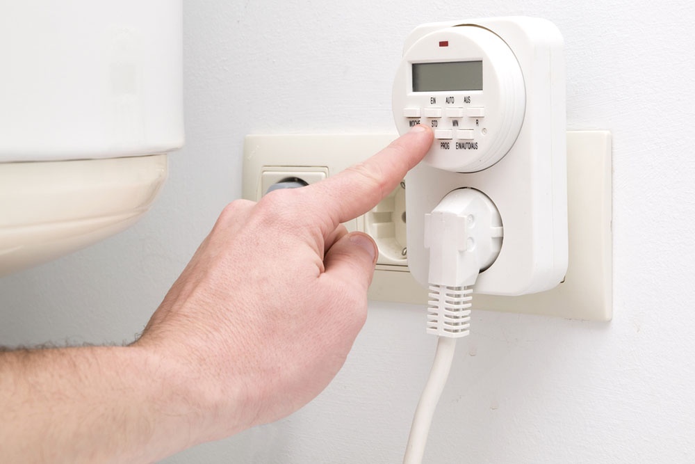 Человек настраивает роботу розетки с таймером для экономии энергоресурсов.