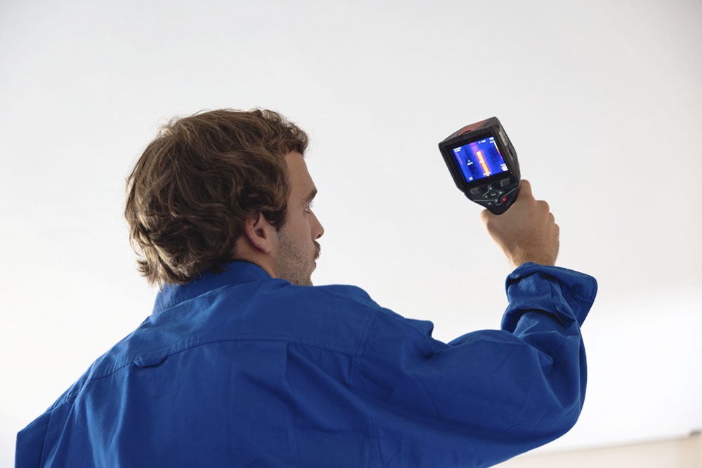 Специалист проверяет потери тепла с помощью тепловизора.