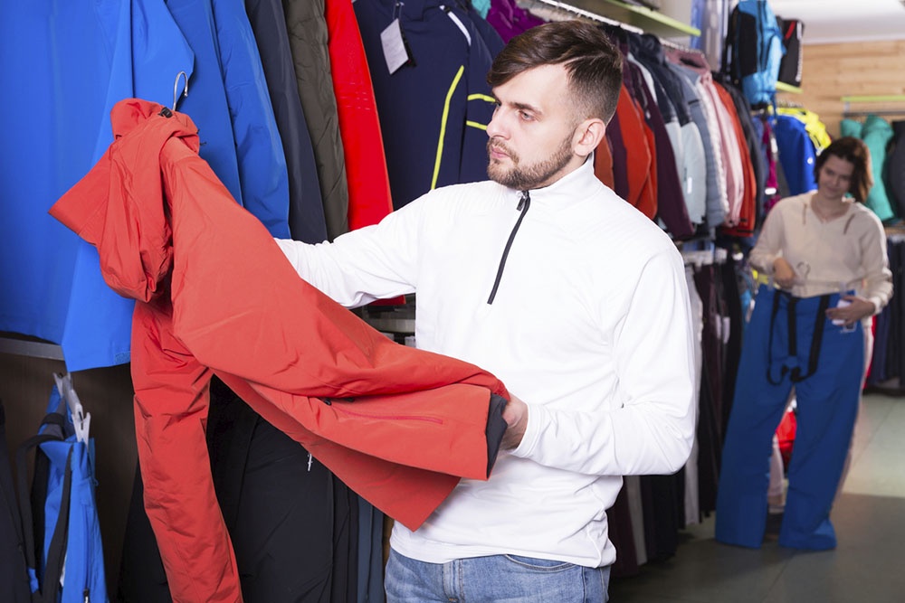 Мужчина и женщина выбирают спортивную одежду в магазине.