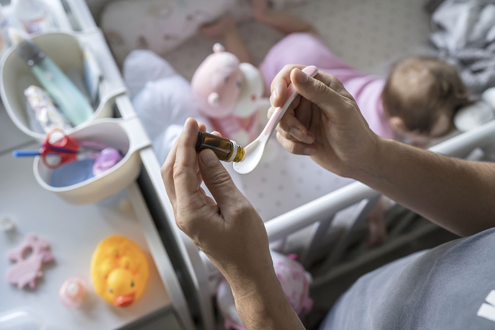 Родитель собирается дать ребенку пробиотик в каплях.