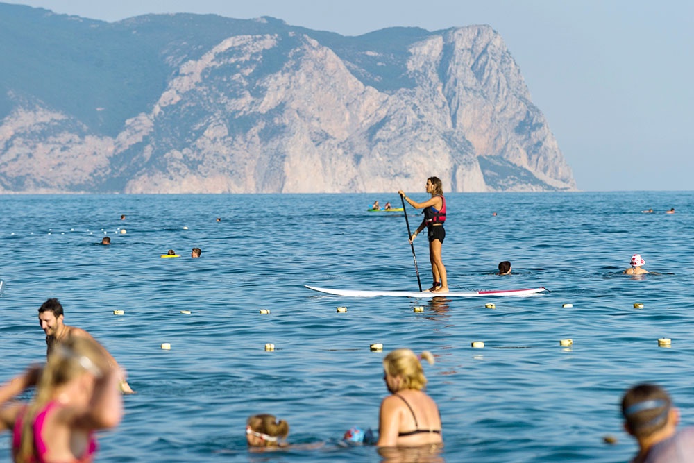 Девушка занимается SUP серфингом в акватории Яшмового пляжа у мыса Фиолент в Севастополе.