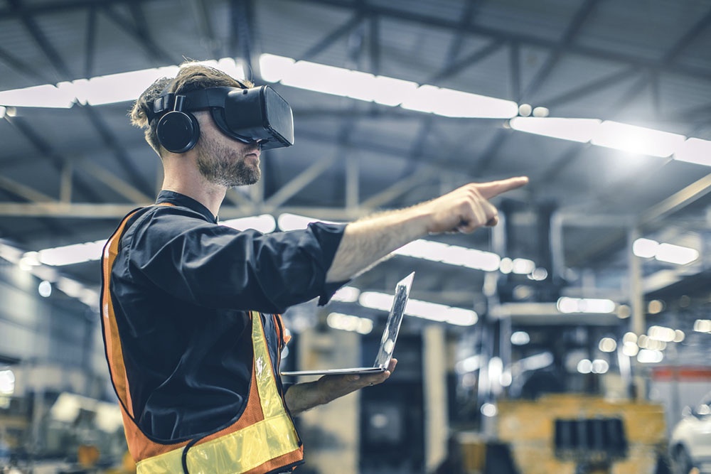 Работник в VR  шлеме собирает конструкцию цеха,  планирует будущий цех.