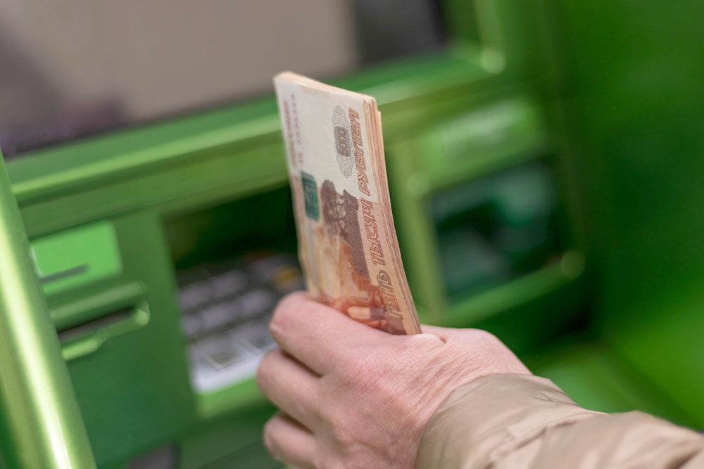 Человек вносит наличные через банкомат на оплату капремонта.