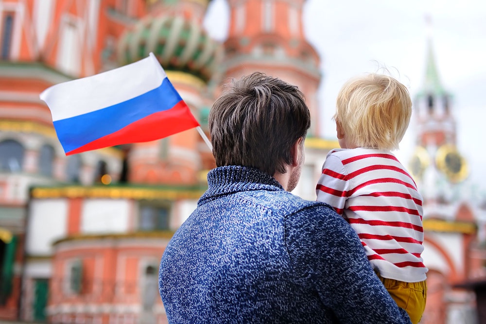 Отец и сын с российским флагом у Кремля. Поздравление с Днем России красивые, написаны своими словами.
