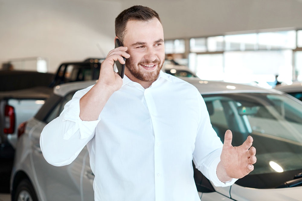Продавец авто разговаривает по телефону с покупателем. Проверка автомобиля перед покупкой.