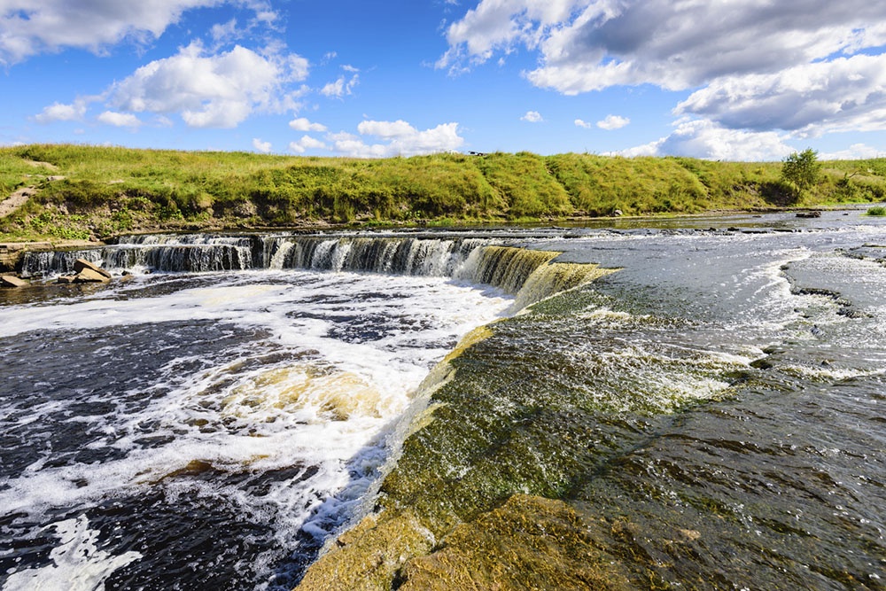 Саблинский водопад на реке Саблинке, каскад воды среди скал и деревьев.
