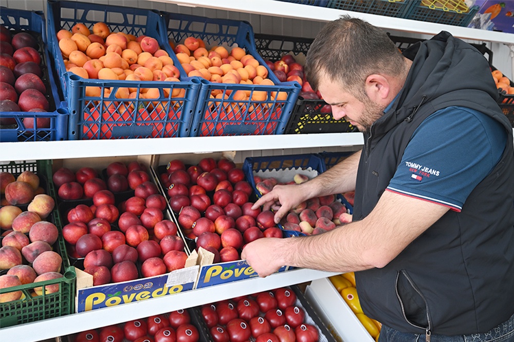 продавец фруктов с ящиками персиков