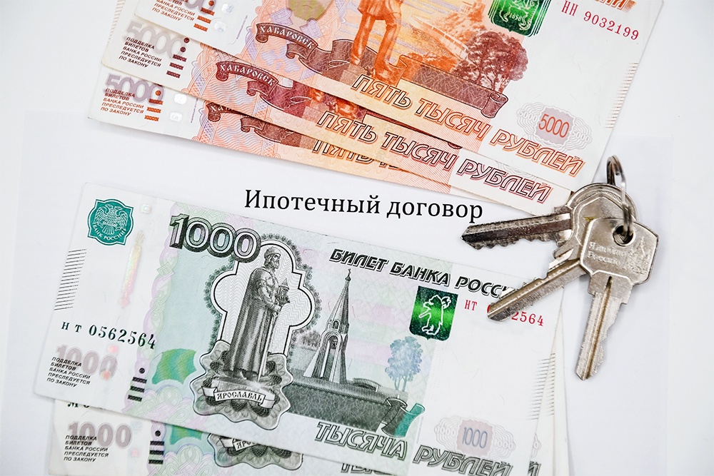 Денежные купюры лежат рядом с ипотечным договором и ключами