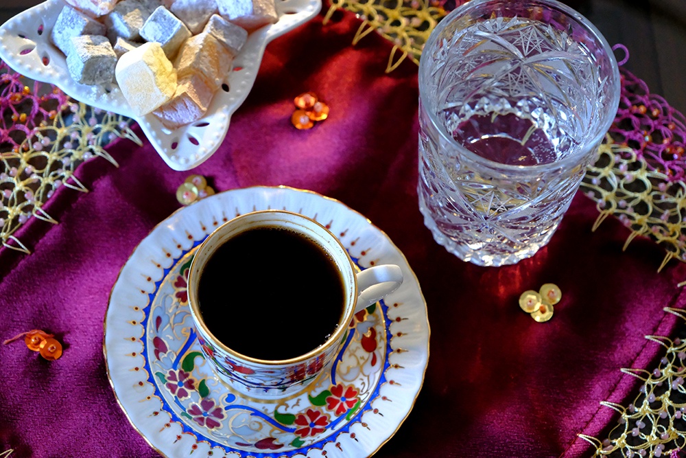Традиционный турецкий кофе и рахат-лукум на бордовой кружевной ткани.