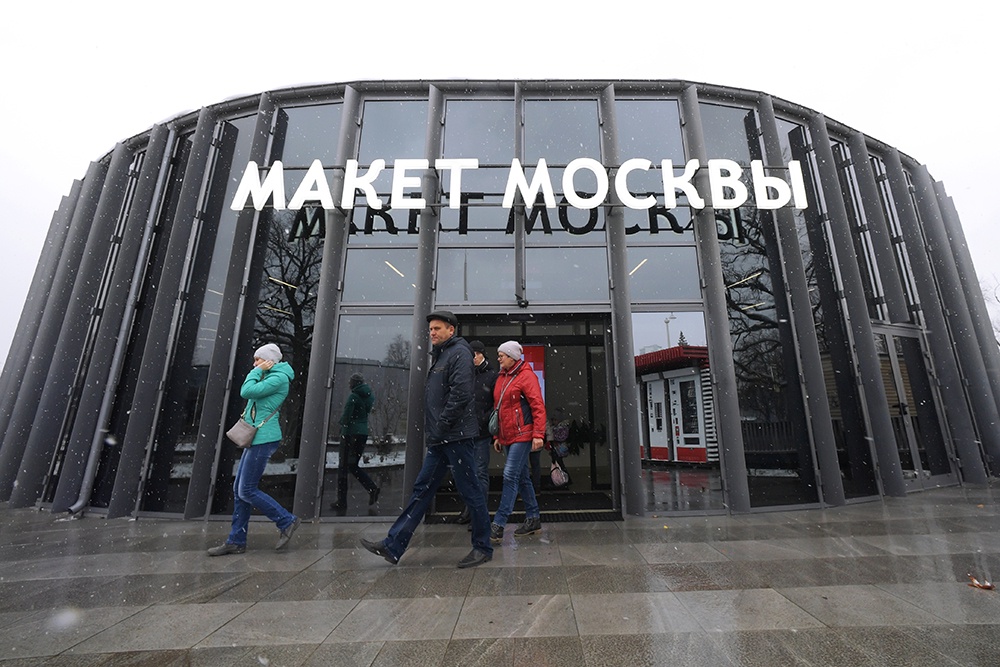 Посетители выходят из здания с архитектурным макетом центра Москвы, на Сиреневой аллее ВДНХ.