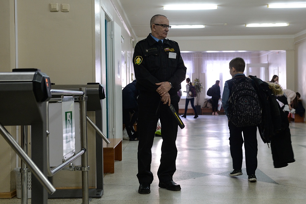 Сотрудник службы безопасности и турникеты на входе в среднюю общеобразовательную школу в Новосибирске.