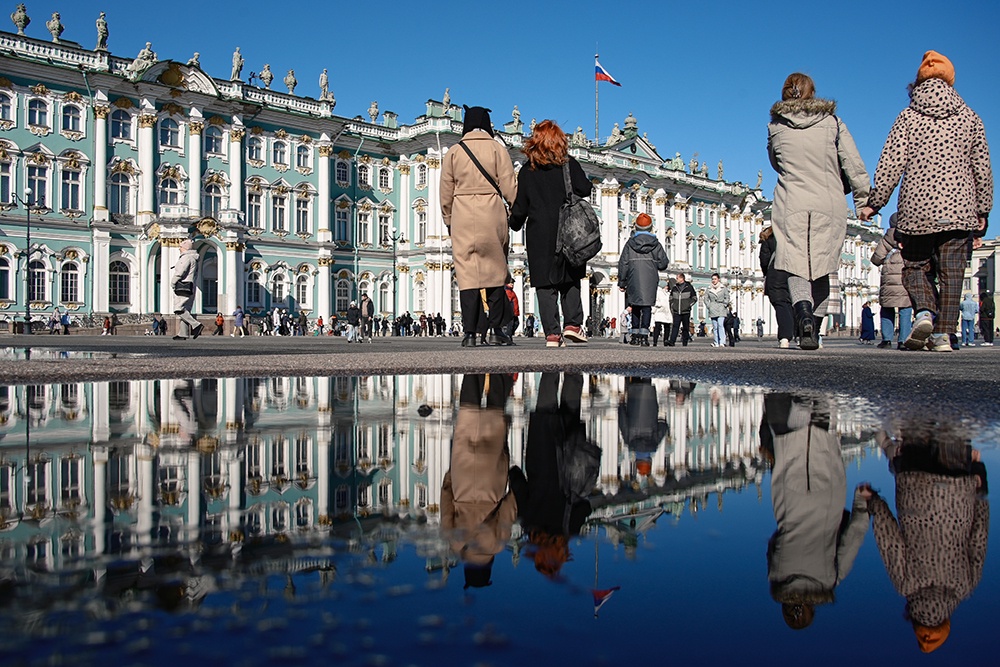 Люди гуляют на Дворцовой площади в Санкт-Петербурге.