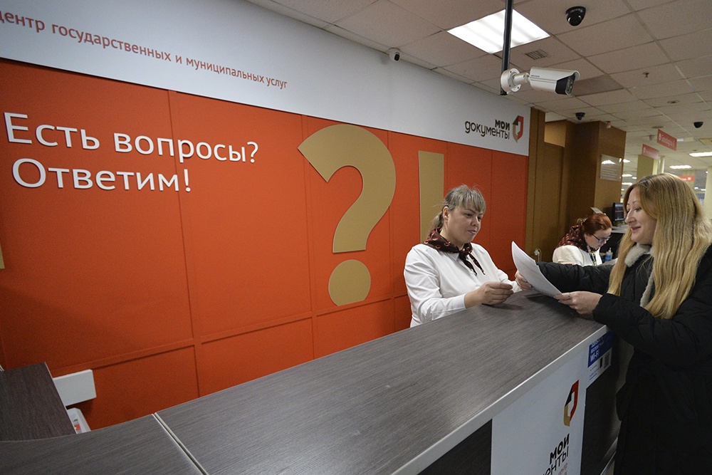 Сотрудник МФЦ консультирует посетителя по вопросам запроса справок.