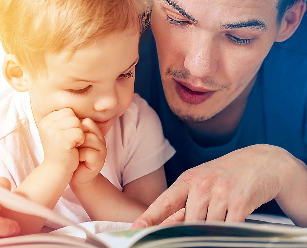 отец читает ребенку книгу
