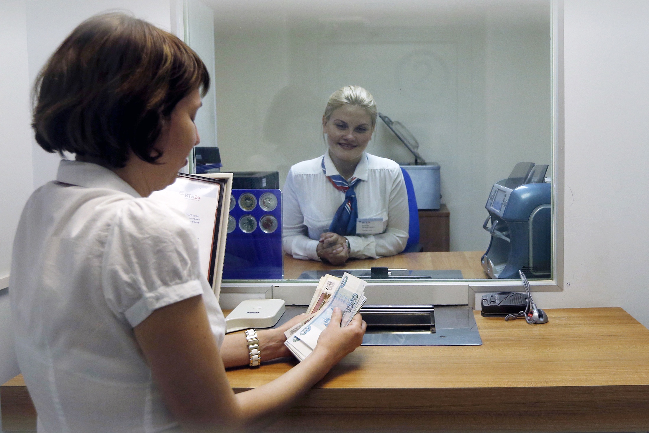 Девушка на кассе в банке считает рубли