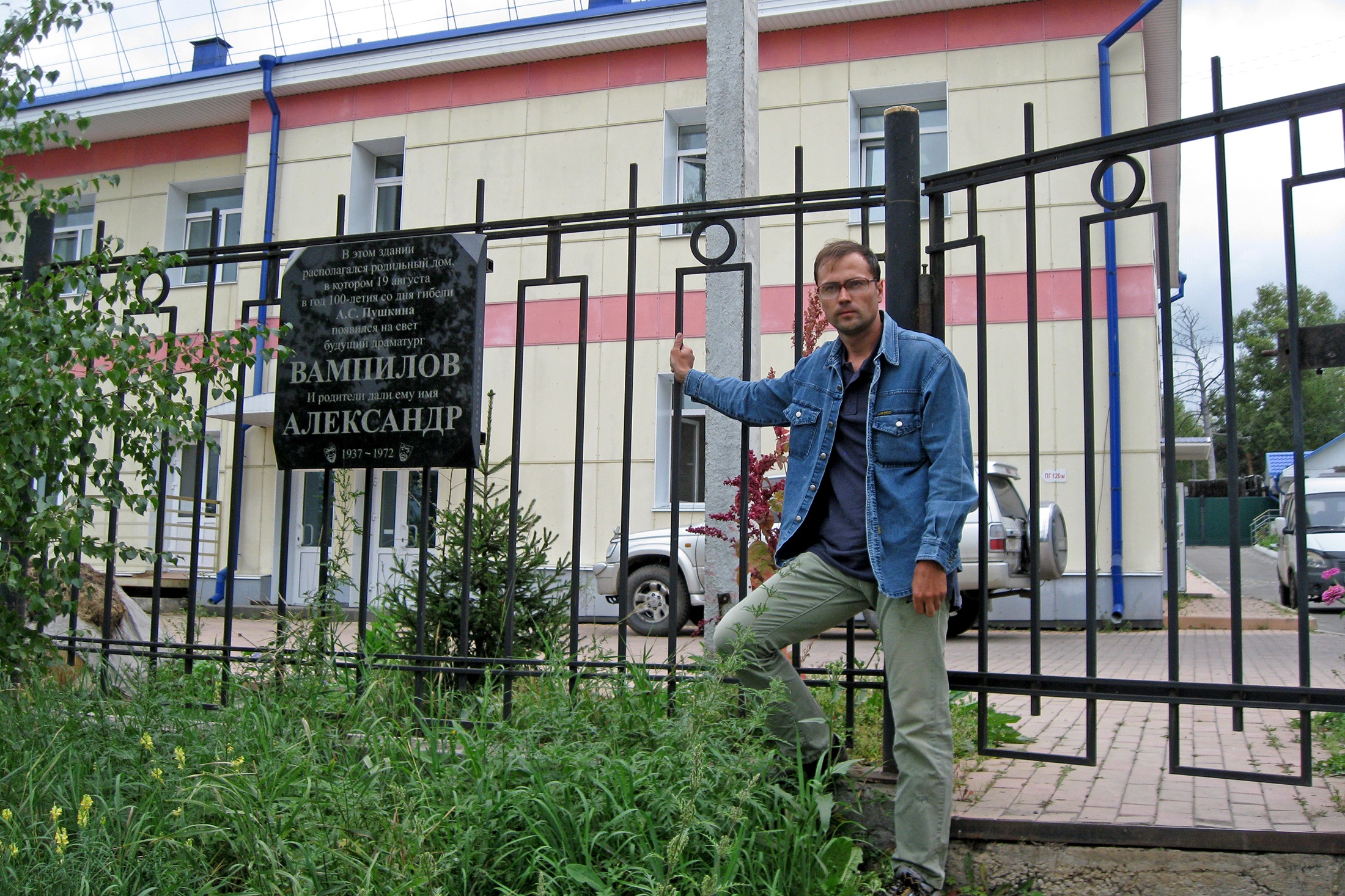 Здание бывшего роддома в Черемхове за забором, на переднем плане Василий Авченко.