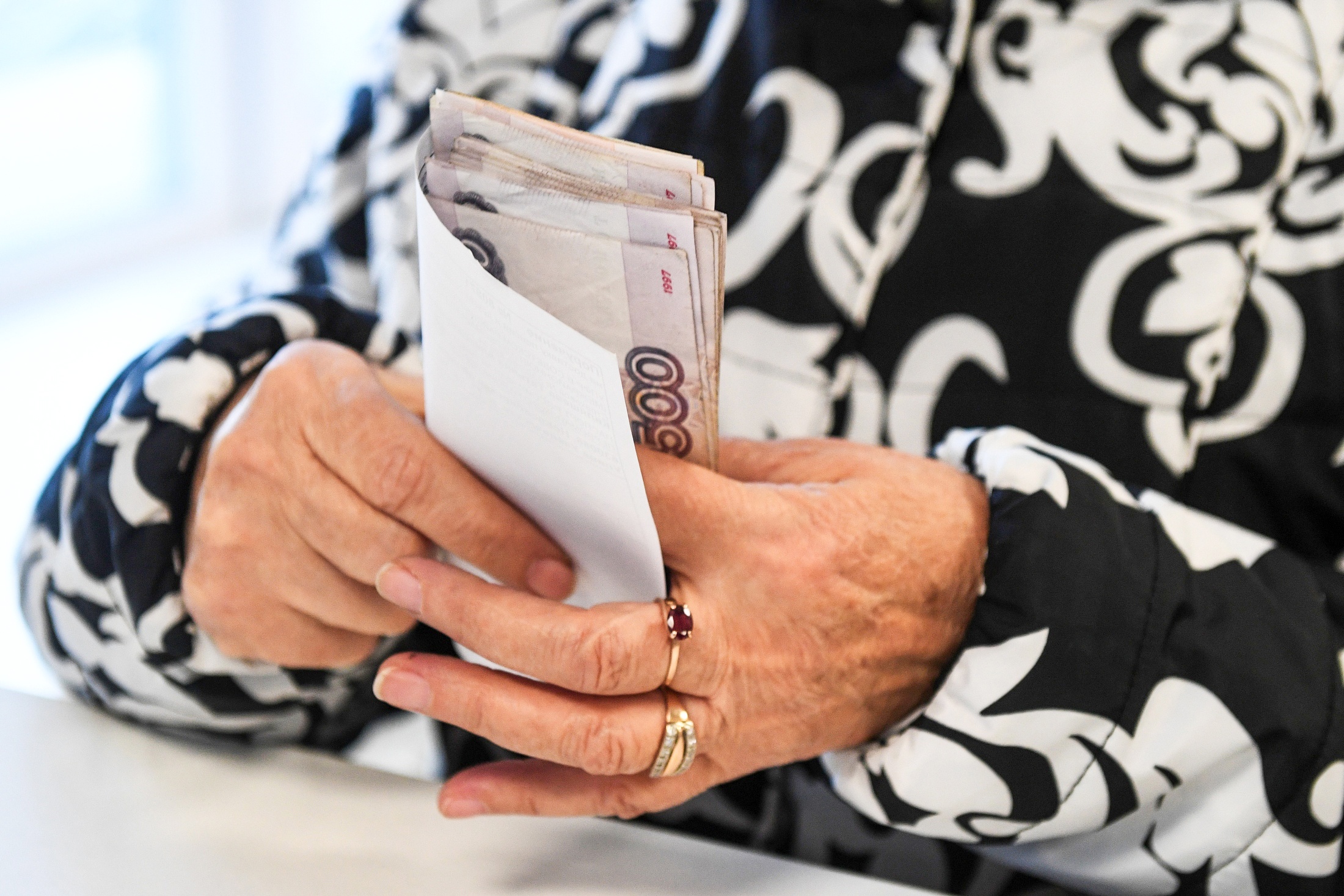 Пенсионерка пересчитывает ежемесячную денежную выплату.