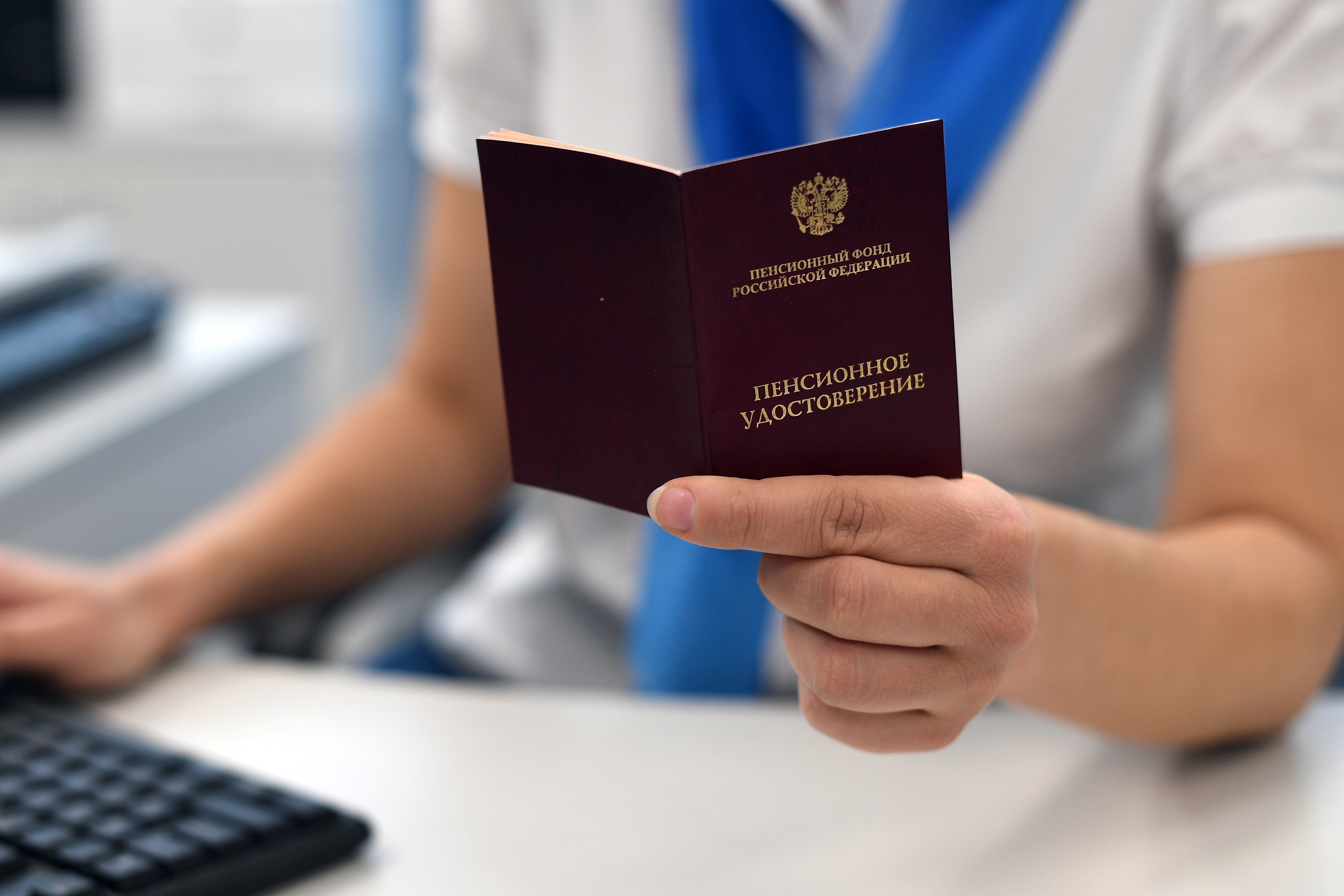 Сотрудница МФЦ проверяет пенсионное удостоверение гражданина.