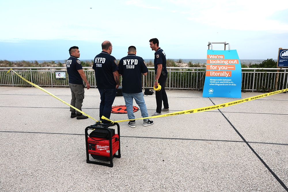 Полицейские собрались вдоль пляжа Рокауэй на 59-й улице после нападения акулы на женщину.