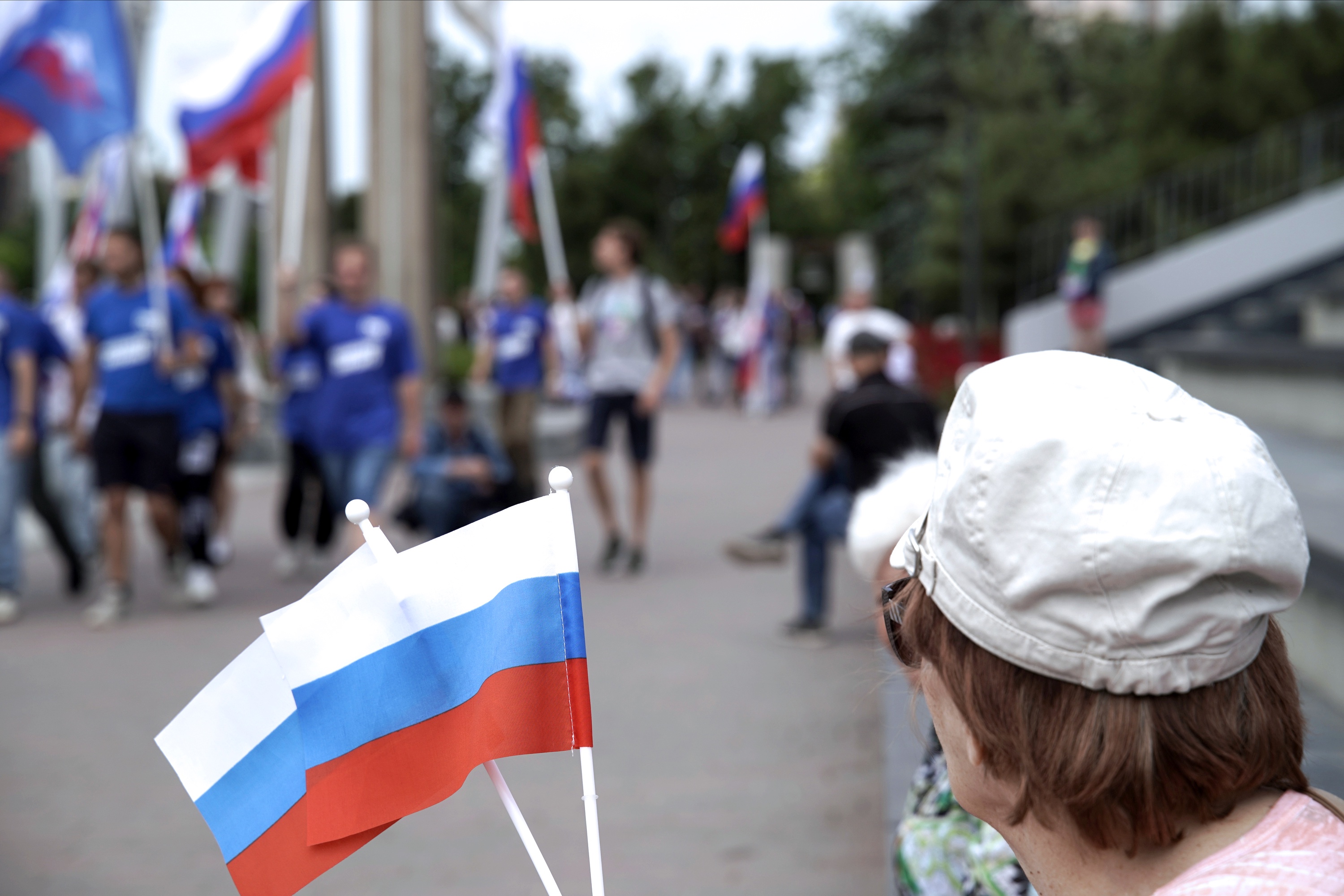 Участники праздничных мероприятий, приуроченных ко Дню России, с флагами РФ на площади Ленина в Мариуполе.
