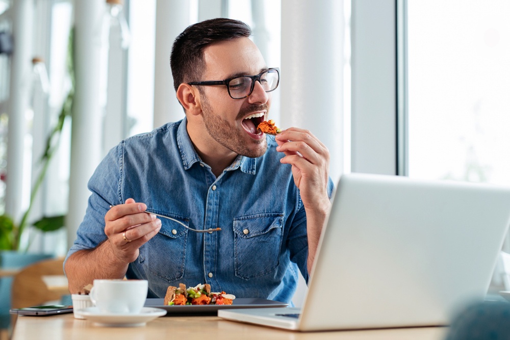 мужчина ест за компьютером