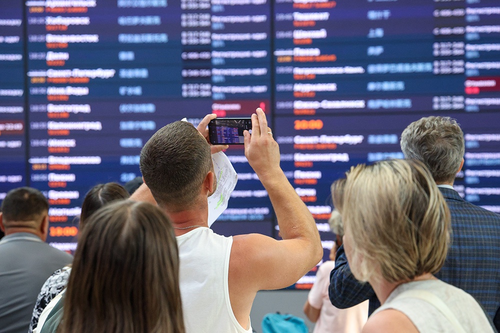 Люди у электронного табло в аэропорту