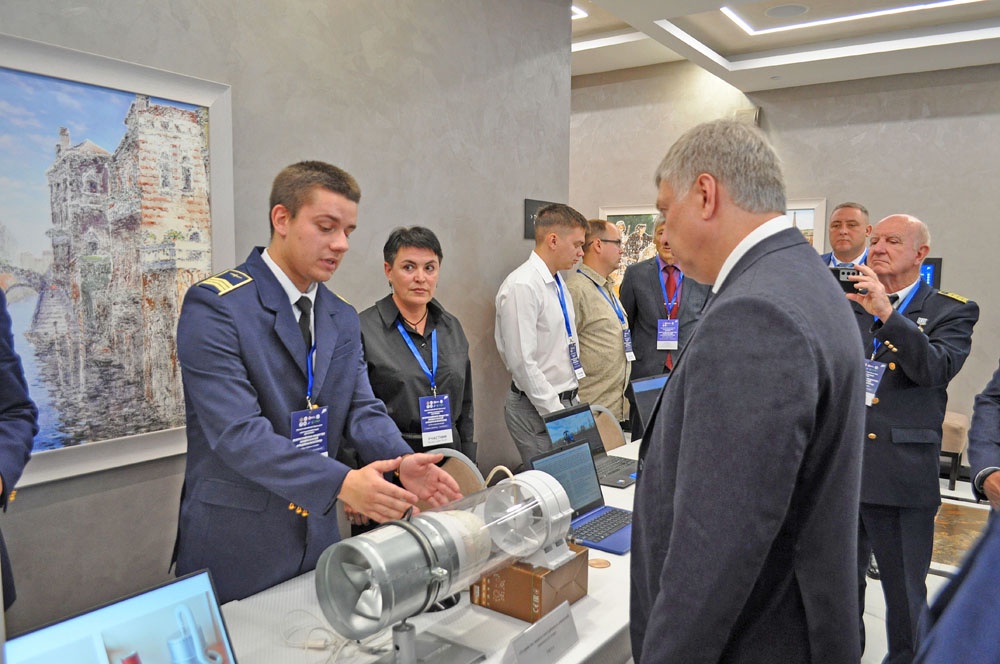 Студент УИГА Максим Гордиеня демонстрирует губернатору макет устройства защиты газотурбинных двигателей самолета от птиц.