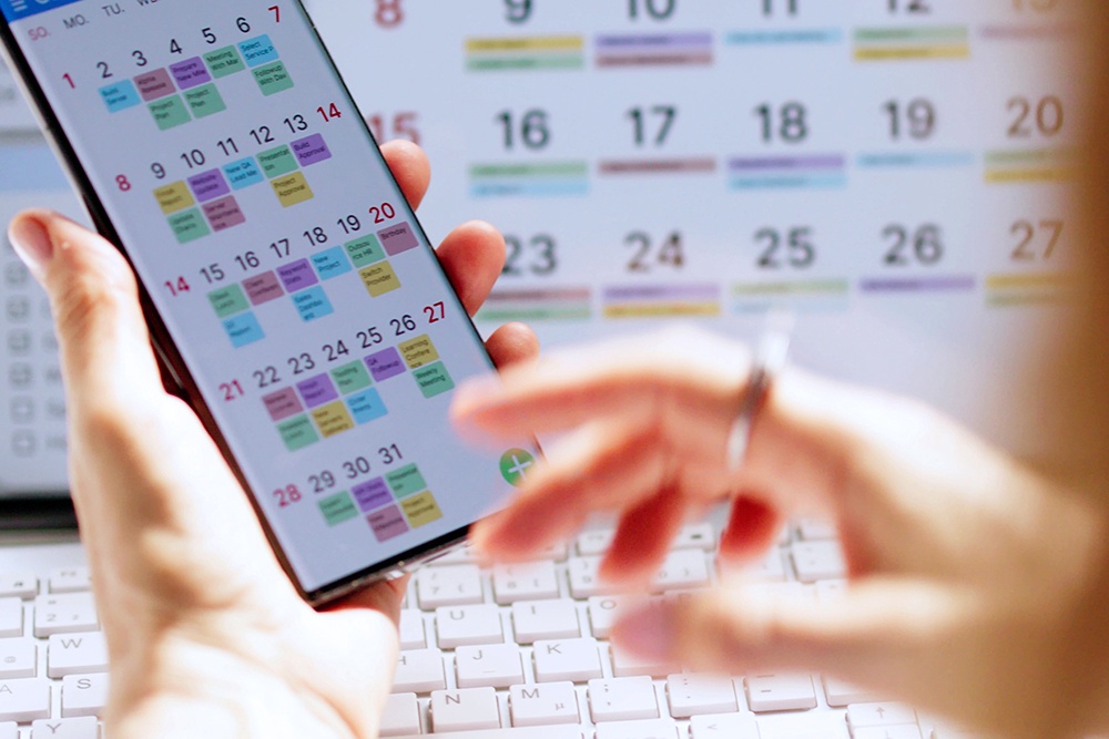 Женщина вносит информацию в календарь на телефоне