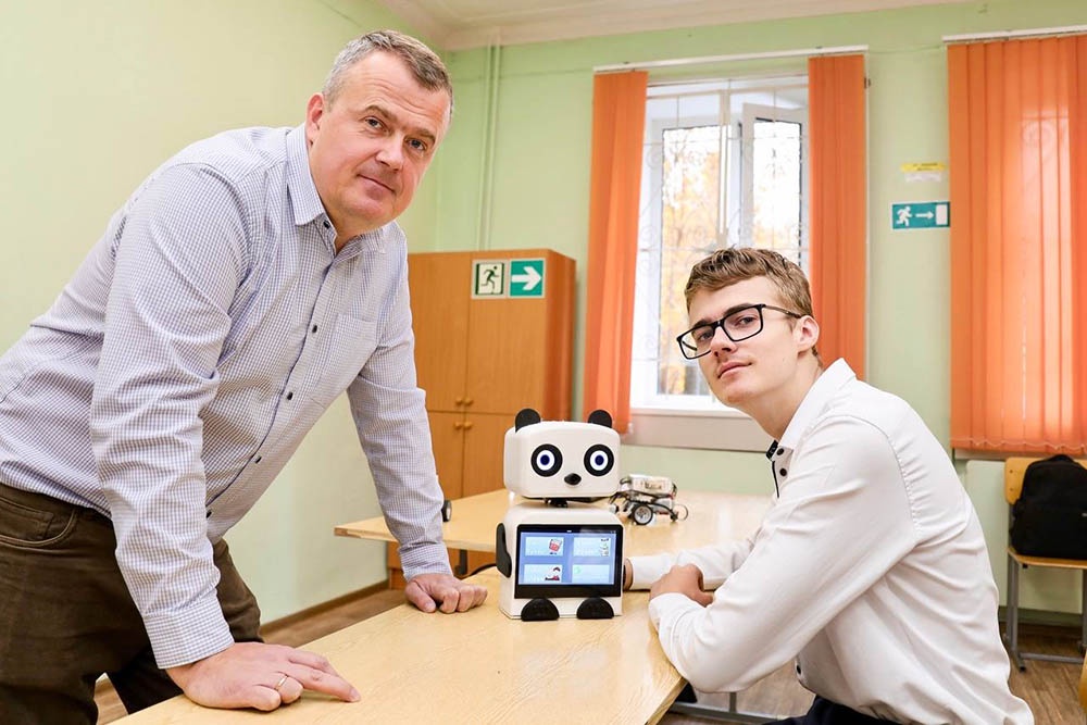Школьник Виталий Симонов (справа) и его робот "Дактик". 